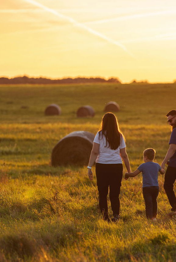 farm family walks across field of round bales